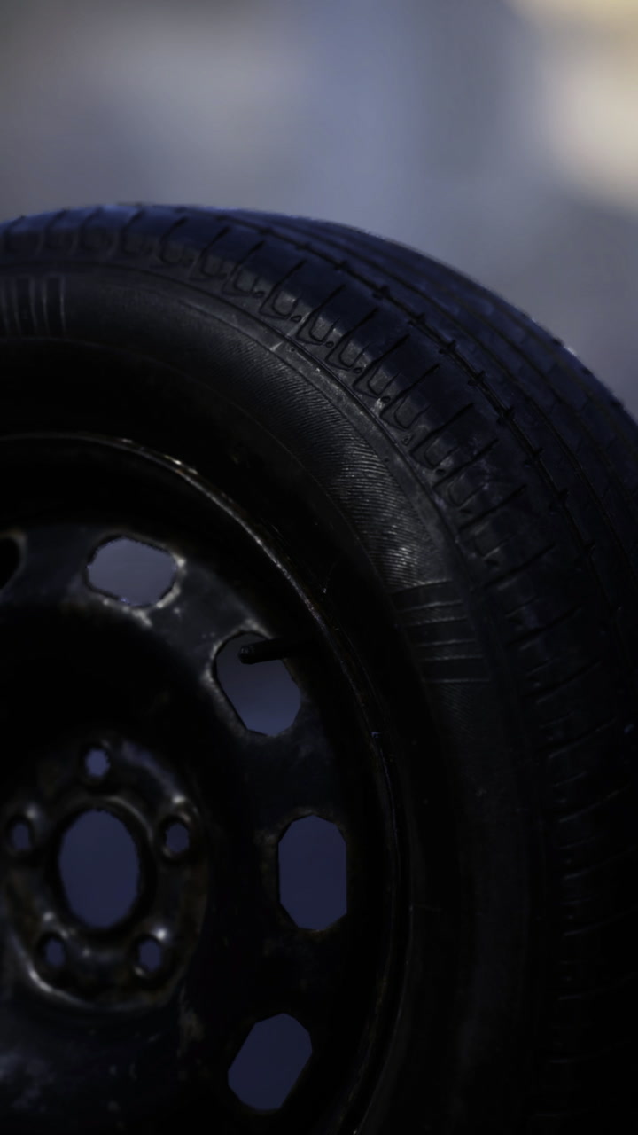 Close up of a textured black tire mounted on a sturdy wheel in natural light