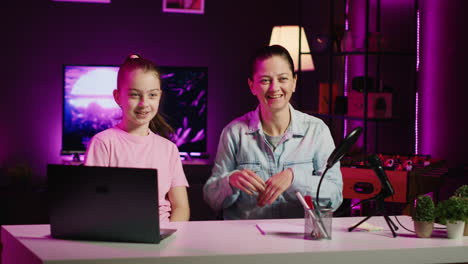 happy daughter and mother in home studio filming video together for social media channels