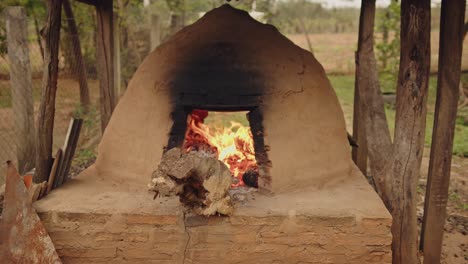 cerca de tatakua, un horno de arcilla tradicional hecho a mano de paraguay, con llamas de madera calentando el horno para más tarde hornear alimentos típicos