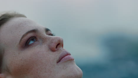 close up portrait of beautiful young woman looking up praying exploring spirituality contemplating future on cloudy seaside