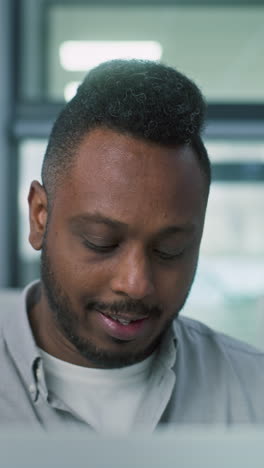 Nervous-African-American-male-voter-chooses-which-presidential-candidate-to-vote-for-in-voting-booth,-looks-at-camera.-US-citizen-at-polling-station-during-Election-Day-in-the-United-States-of-America