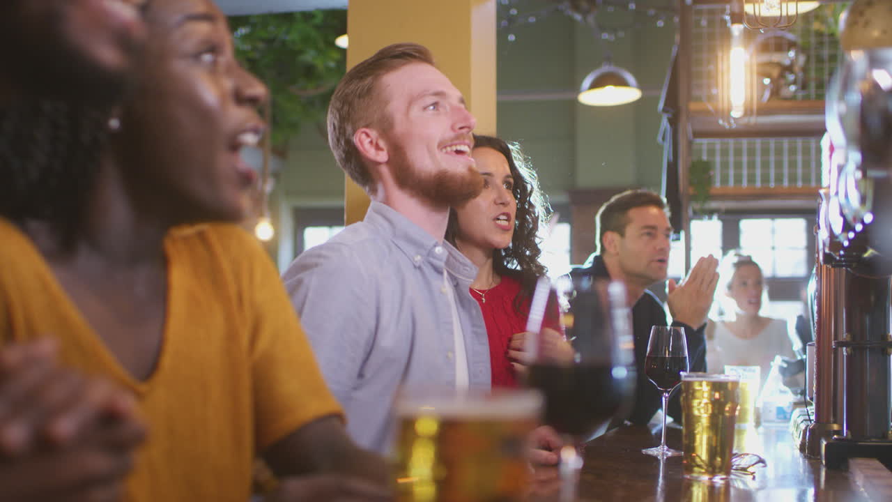 Un gruppo di clienti eccitati in un bar sportivo che guardano un evento sportivo in televisione