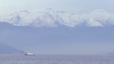 A-small-boat-cross-a-lake-in-front-of-the-Alps-in-Italy-or-Switzerland