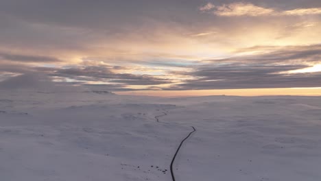 sunset shot of a long arctic mountain road with snow covered mountains