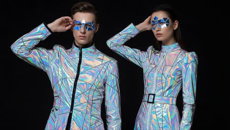 futuristic fashion showcase: models displaying iridescent outfits and geometric sunglasses in a high-contrast studio setting