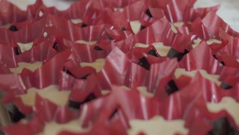 close-up of a pastry chef pouring batter into cupcake liners for baking