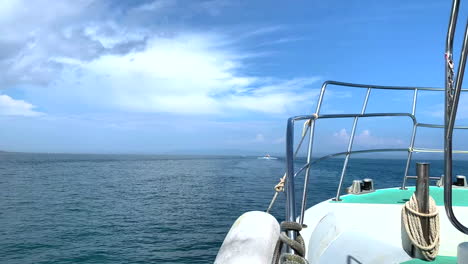 a boat sails in the sea towards the horizon behind another ship seen from the bow under a beautiful clear blue sky on a sunny day in amakusa dolphin japan