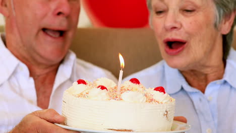 Senior-couple-sitting-on-couch-celebrating-a-birthday