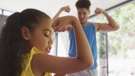 Happy-biracial-father-and-daughter-doing-yoga,-stretching-together