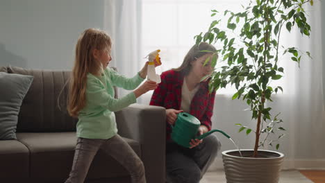 little girl sprays ficus sister waters potted plant at home