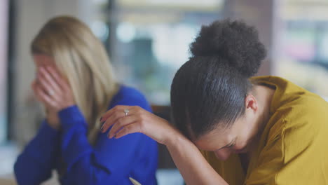 close up of laughing businesswomen having meeting sitting around table in modern open plan office