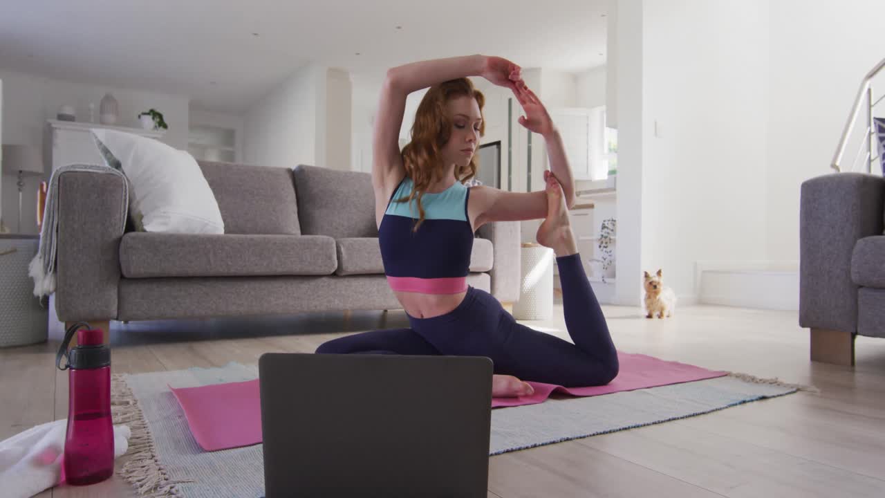 mujer practicando yoga mientras mira en la computadora portátil en casa