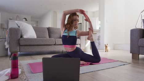 Mujer-Practicando-Yoga-Mientras-Mira-En-La-Computadora-Portátil-En-Casa