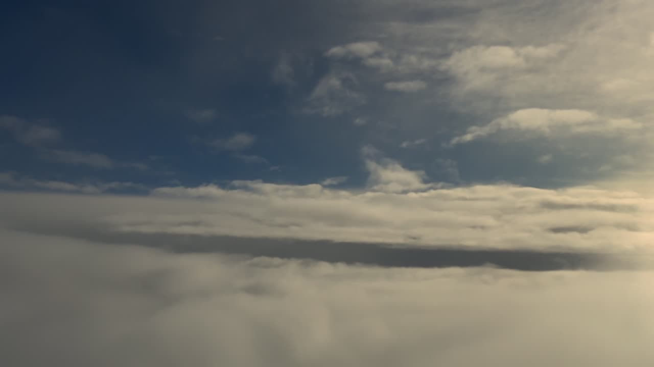 Cockpit view emerging from a layer of ethereal stratus clouds into a blue clear sky with an endless layer of clouds ahead