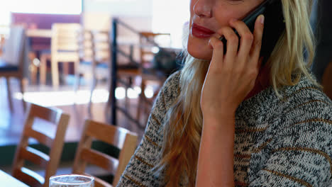 woman talking on mobile phone while having beer at bar 4k