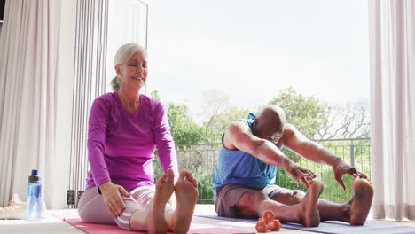 Happy-senior-diverse-couple-practicing-yoga-and-stretching