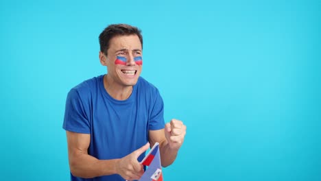 Nervous man cheering for Haiti during a match looking away
