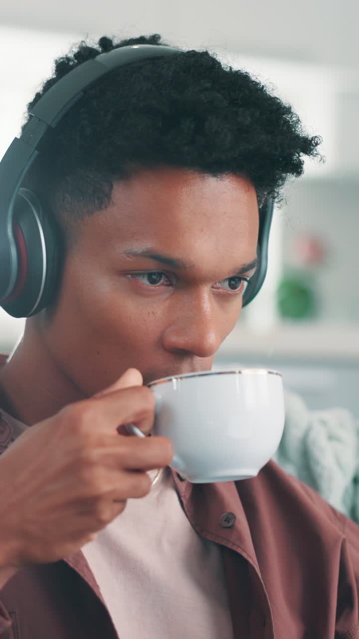 Ung mand med høretelefoner på og drikker kaffe