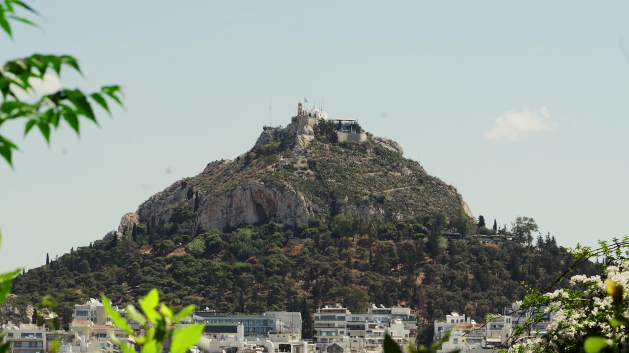 Il Monte Licabetto e i suoi edifici in cima alla collina si ergono sopra gli appartamenti residenziali circostanti ad Atene in una limpida giornata estiva
