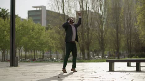 Excited-businessman-talking-by-cell-phone-outdoor