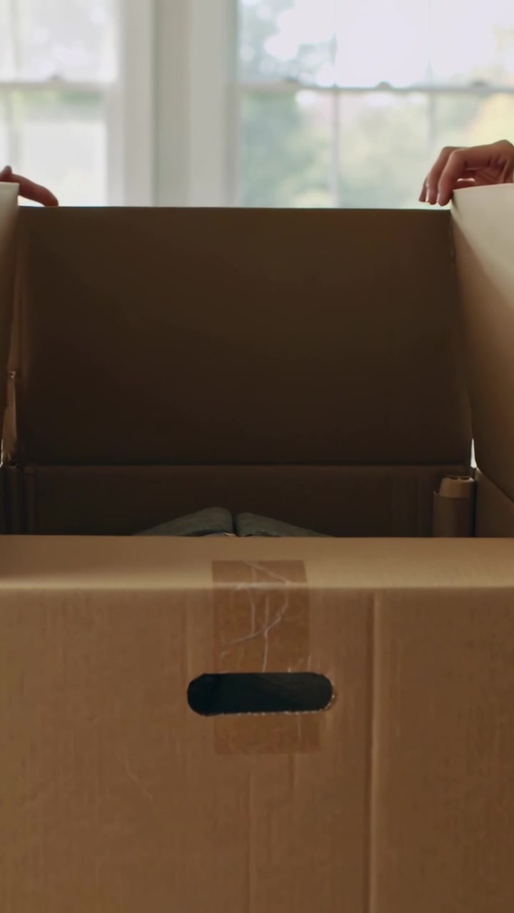Vertical video: Peeling tape, two people in denim, cream knit opening box at home to check blanket