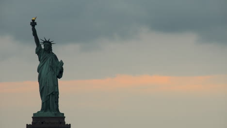 statue of liberty at sunset with clouds slowly passing