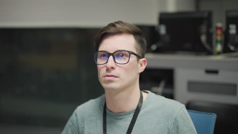 focused young professional working with multiple monitors in modern office setting. individual wearing glasses, staring at screen analyzing technical data or information