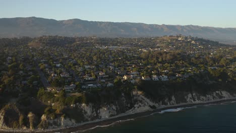 Drone-Flies-Toward-Coastal-California-Town-on-Summer-Day,-Mountains-in-Background