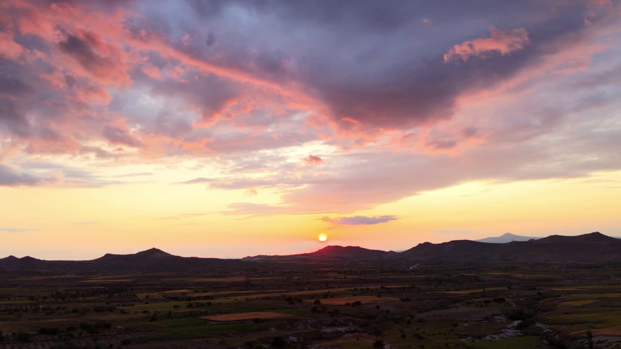 Colorful sunset over mountains and fields creating a serene evening mood