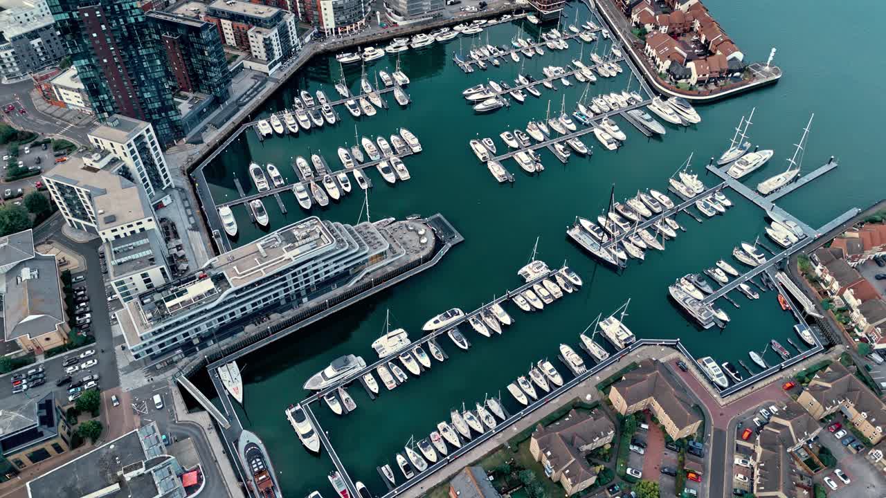 Aerial drone footage of Ocean Village marina in Southampton, showcasing boats, docks, buildings, and waterfront real estate under soft daylight at sunset shot during autumn