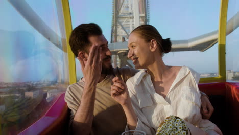 young couple eating popcorn on a ferris wheel