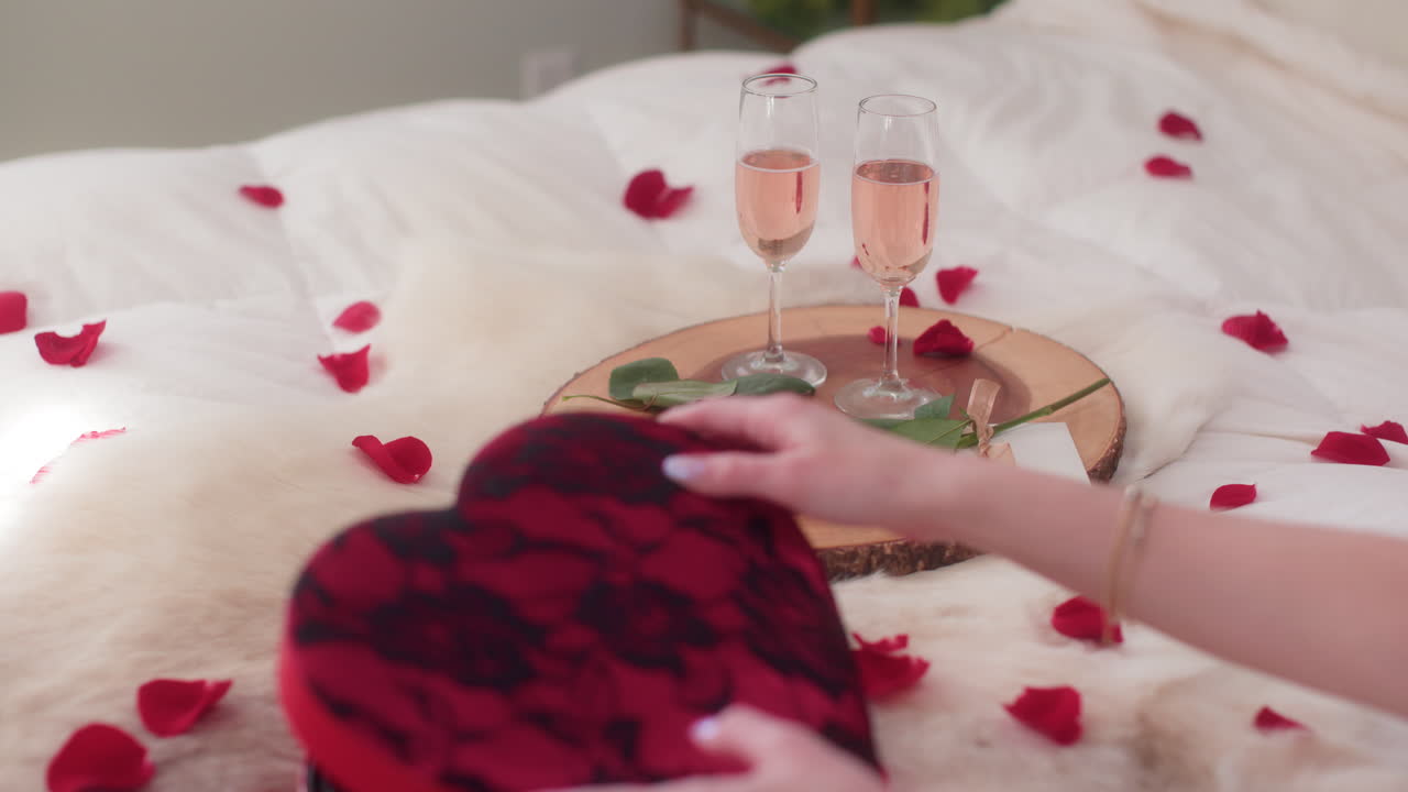 Sparkling rose wine on wooden platter, woman grabbing Valentine's Day chocolates