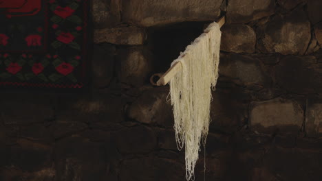 Maturing-cheese-strings-hanging-on-wooden-rack-in-traditional-creamery