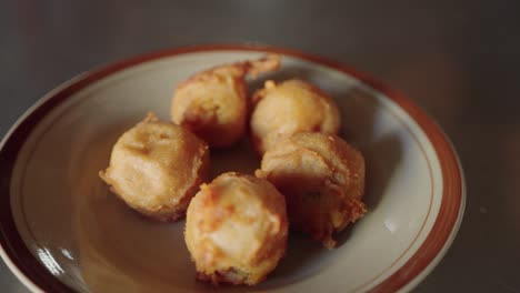 hand placing fried food balls on a plate