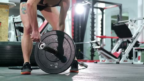 athletic woman bodybuilder training to do exercises with barbell in gym, hold barbell plate in hands, sport man
