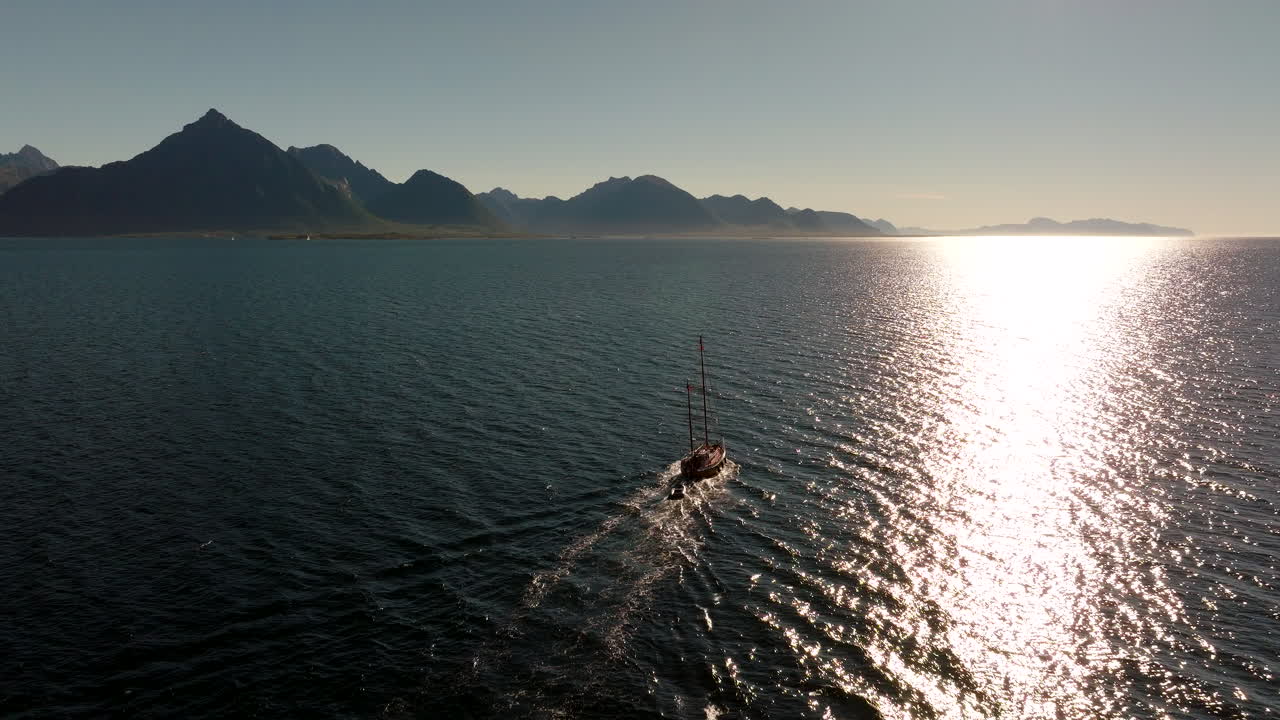 Drone Shot Following Boat Sailing Along Rugged Coast of Norway. Extreme Water Adventure Travels