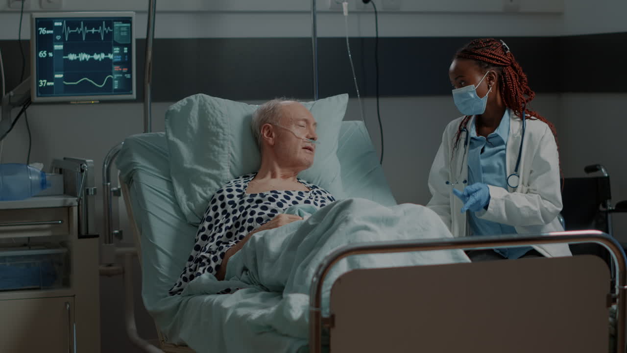 African american medic talking to sick patient in hospital ward