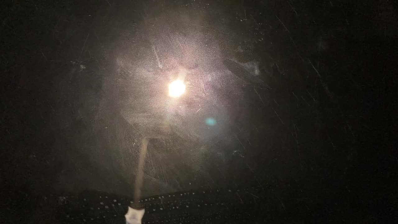 비가 뉴질랜드 가정집에서 가로등으로 어두운 밤에 차 유리에 부딪쳤다.