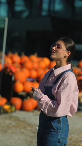 mujer joven con camisa rosa y mono de vaqueros en el parche de calabazas