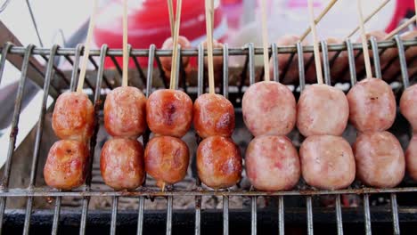 A footage revealing short sausages captured from the front side as they are placed on a grill, Street Food along Sukhumvit Road in Bangkok, Thailand