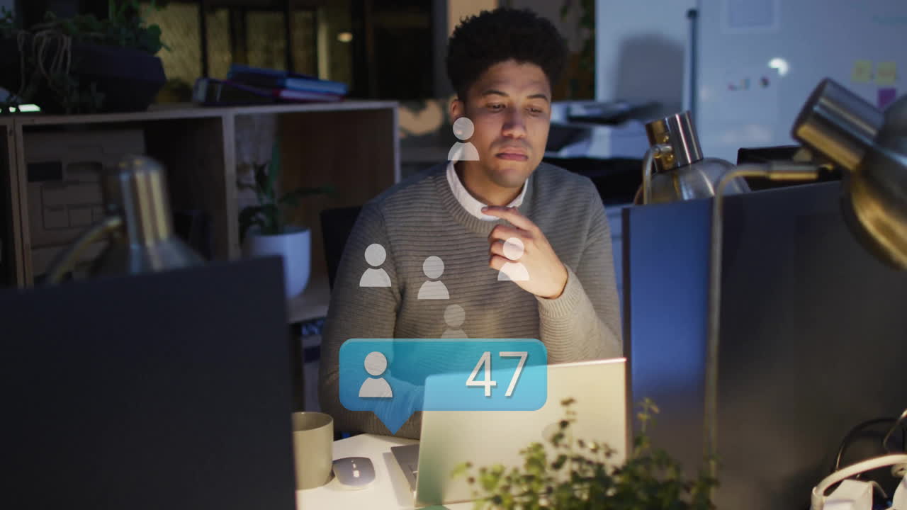 Working late in office, man using laptop with animation on screen