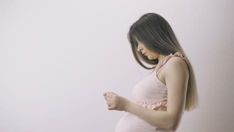 분홍색 드레스를 입은 임신한 여성이 방의 온도를 측정합니다.