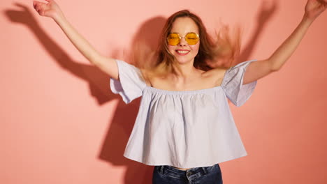 playful woman in a light blue top and yellow sunglasses