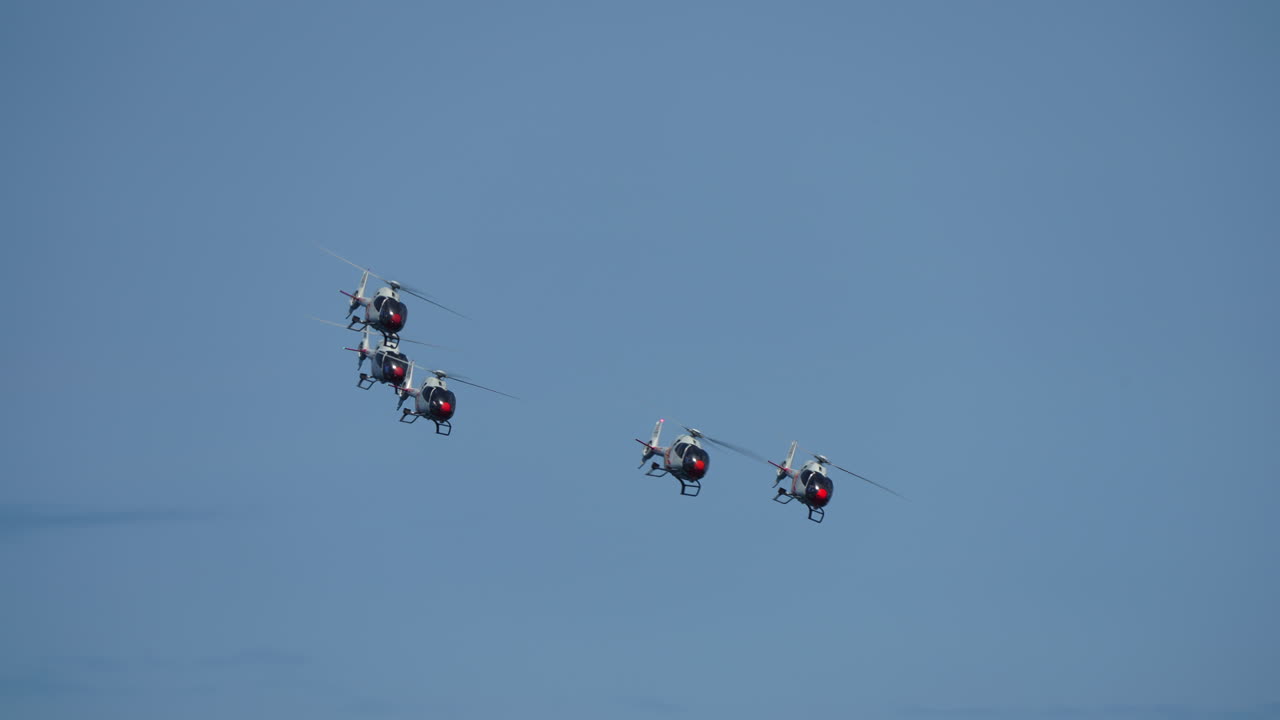 Synchronized military helicopters performing precise aerial formation flight, demonstrating exceptional piloting skill against pristine blue sky backdrop