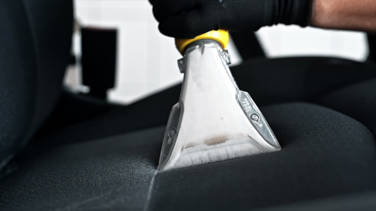 Working cleaner at car wash. Cleaning a seat using a professional vacuum cleaner. Slow motion