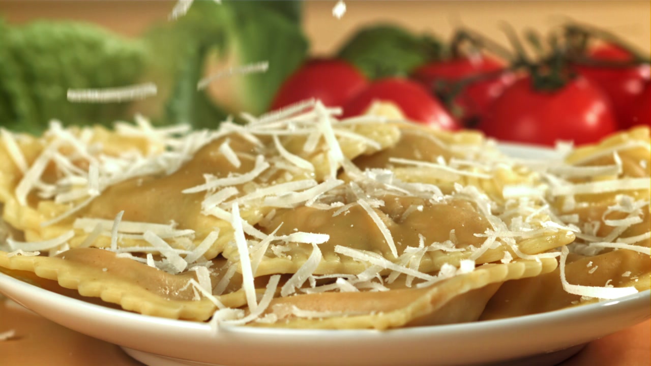 Parmigiano grattugiato che cade su ravioli freschi