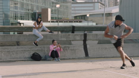 Tanzender-Mann,-Junger-Mann-Gemischter-Abstammung,-Straßentänzer,-Breakdance-Freestyle-Moves,-Der-Einen-Backflip-Ausführt,-Freunde,-Die-Mit-Dem-Smartphone-Zuschauen,-Videos-Aufnehmen-Und-Den-Tanz-In-Der-Stadt-Genießen