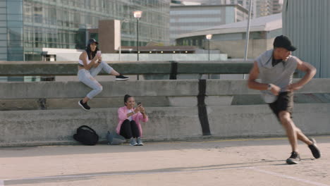 hombre bailando joven bailarín de calle de raza mixta hombre bailando breakdance movimientos de estilo libre realizando salto hacia atrás amigos viendo usando teléfono inteligente tomando video disfrutando del baile en la ciudad