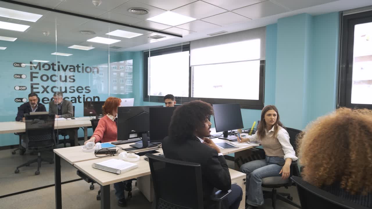 Happy multiethnic colleagues discussing and working on computers in creative workspace