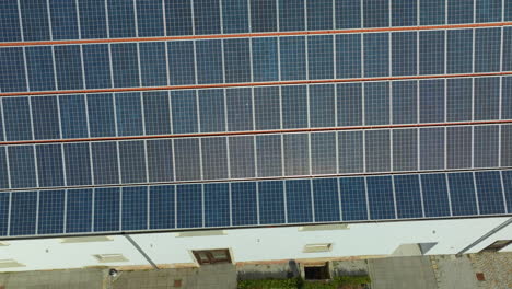 Overhead-view-of-dense-solar-panels-neatly-lining-a-building's-roof,-converting-sunlight-into-clean-energy